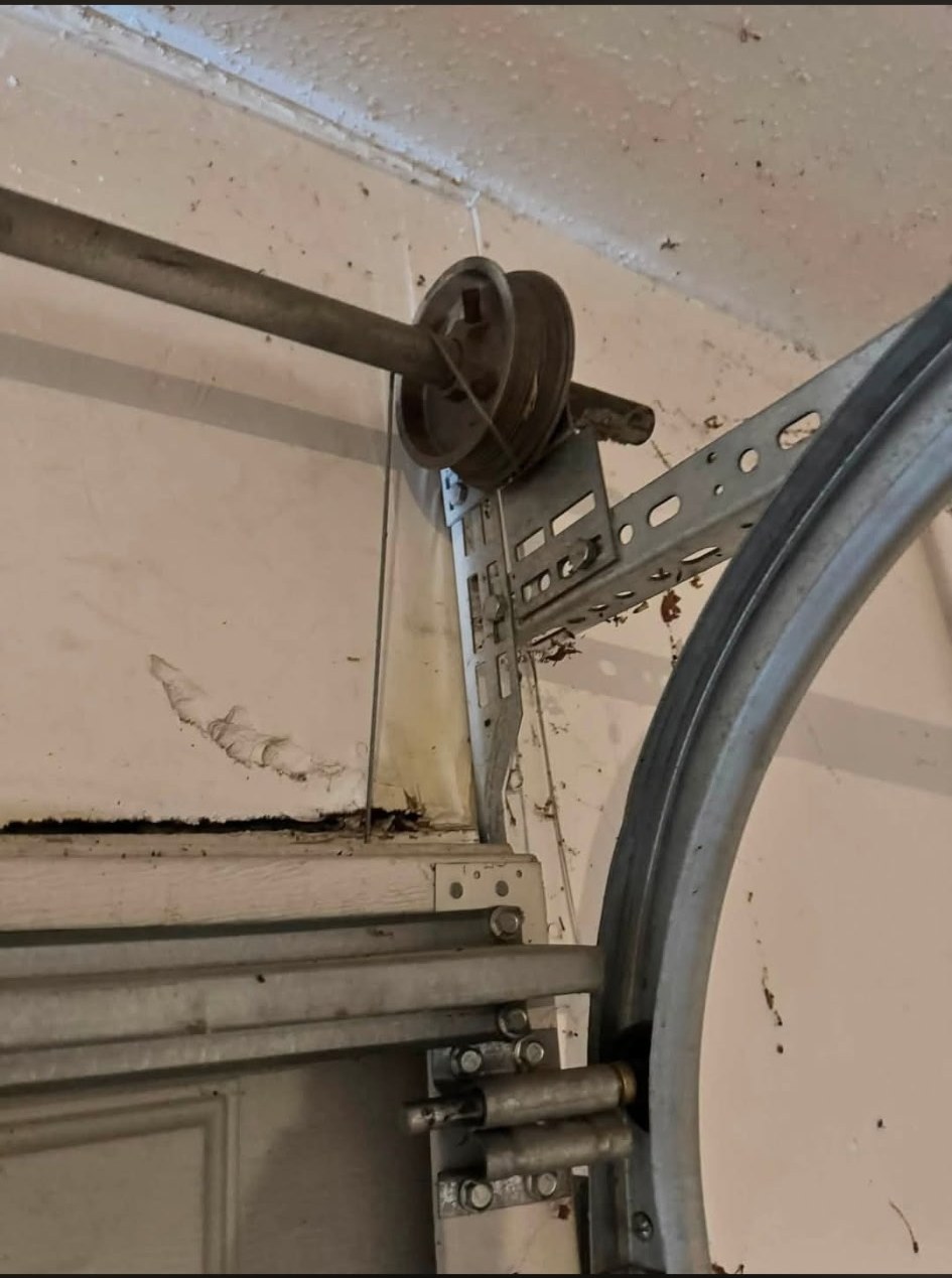 A worn pulley and frayed garage door cable